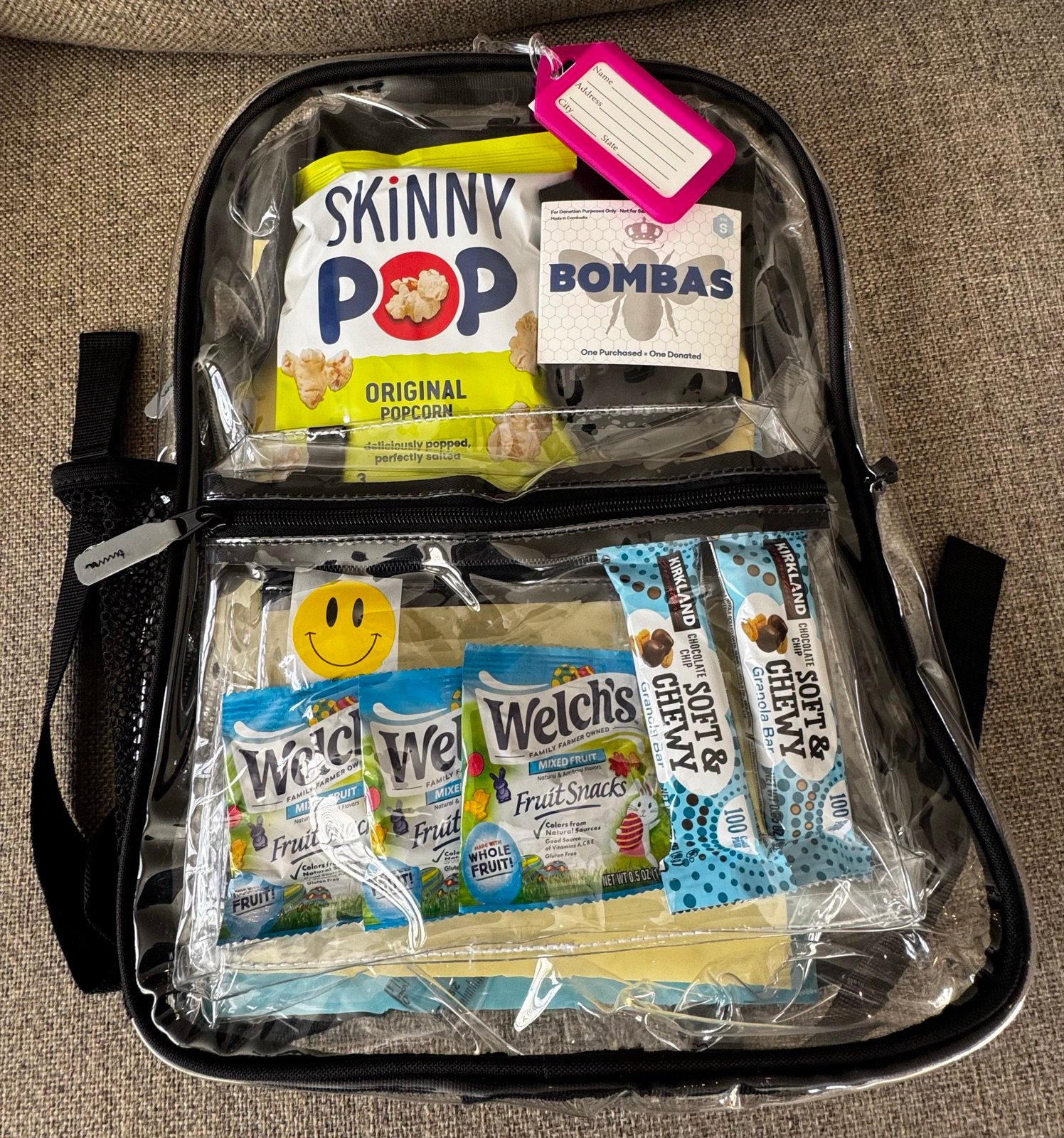 A clear backpack packed with snacks and Bombas socks